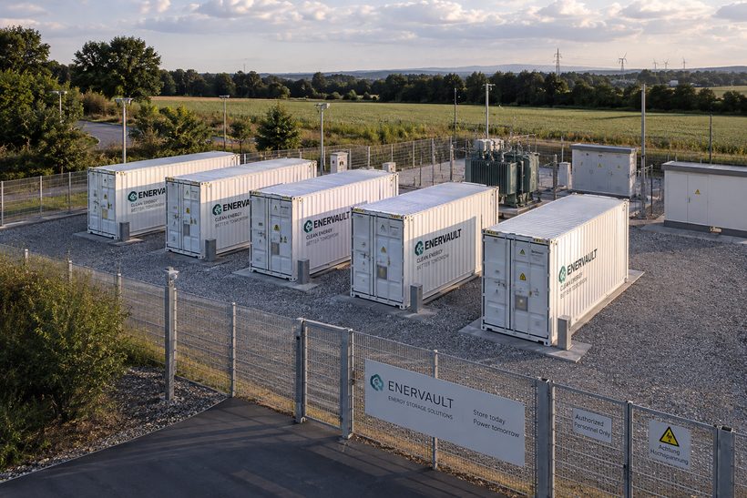 F&uuml;nf wei&szlig;e Batteriespeicher-Container mit Trafostation auf einem eingez&auml;unten Gel&auml;nde